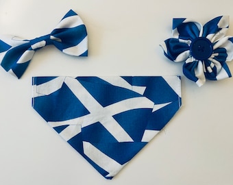May include: A collection of pet accessories in a blue and white pattern, including a bow tie, a bandana, and a flower. The items are arranged on a white surface. The design is reminiscent of a flag.