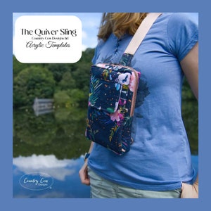 May include: A woman wearing a blue shirt and jeans is wearing a crossbody bag with a floral print. The bag is called "The Quiver Sling" and is made by Country Cow Designs. The bag has a zipper closure and a strap that goes over the shoulder.
