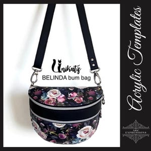 May include: A black bum bag with a floral pattern of pink and purple roses. The bag has two zippered compartments and a black adjustable strap. The text "Unikatz BELINDA bum bag" is printed on the bag.