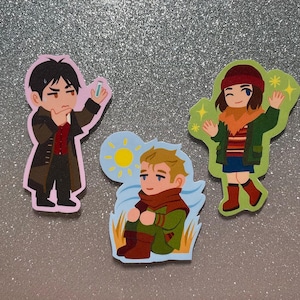 Puede incluir: Tres personajes ilustrados sobre un fondo plateado. Un hombre con cabello oscuro y un atuendo rojo y negro, una mujer con cabello largo castaño que lleva una chaqueta roja y verde, y un hombre con cabello rubio que lleva una chaqueta verde y una bufanda.