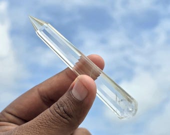 以下が含まれることがあります： 透明で無色なクォーツクリスタルのポイントで、研磨された六角形のファセット形状をしています。クリスタルは細長く、一方の端は鋭い先端に向かって先細りになっており、もう一方の端は平らです。表面は滑らかで光を反射します。