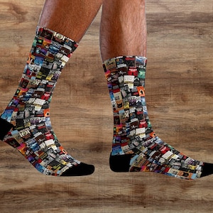 Peut inclure: Une paire de chaussettes noires avec un imprimé coloré de couvertures de livres. Les chaussettes sont faites d'un matériau doux et confortable et sont parfaites pour un usage quotidien.