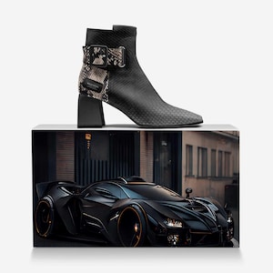 May include: A black and gray high-heeled ankle boot with a snakeskin pattern on the side and a buckle closure. The boot is on a white surface in front of a black sports car.