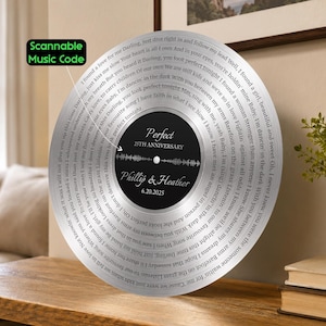 May include: A circular silver-toned plaque designed like a vinyl record featuring the lyrics to the song Perfect, a scannable music code, the text 25th Anniversary, the names Phillip & Heather, and the date 6.20.2025 printed on the black center label.