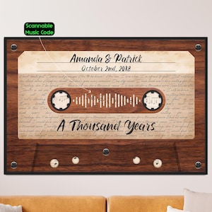 May include: A rectangular wall art print featuring a wood grain pattern shaped like a cassette tape. It displays the names Amanda & Patrick, the date October 2nd, 2018, the song title A Thousand Years, lyrics, a scannable music code, and musical notes.