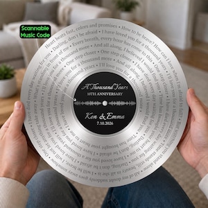 May include: A circular silver-toned commemorative plaque designed like a vinyl record. The center black label features the text A Thousand Years, 10th Anniversary, Ken & Emma, 7.10.2026, and a sound wave graphic. Lyrics are engraved in a spiral pattern.