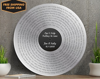 Op de afbeelding: Een zilveren ronde plaat met een zwart middenstuk met de tekst van het nummer "Can't Help Falling in Love" van Elvis Presley. De tekst op de plaat luidt "Can't Help Falling in Love" met de namen "Jim & Kelly" en de datum "12.11.2022" eronder.