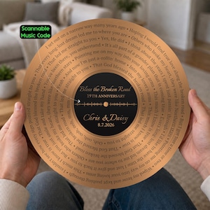 May include: A circular copper-colored plaque resembling a vinyl record, featuring lyrics from "Bless the Broken Road" spiraling around the center. The black center label displays "Bless the Broken Road," "19TH ANNIVERSARY," "Chris & Daisy," and "8.7.2026" with a sound wave graphic.