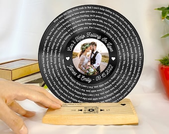 May include: Black vinyl record with a photo of a couple in a wedding setting. The record has the text "Can't Help Falling In Love" and the date "09.15.2022" with the names "James & Emily".
