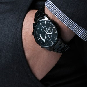 May include: A black chronograph wristwatch with a black metal band. The watch face has a black background with white hour and minute hands, a red second hand, and a date window.