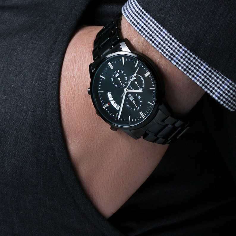 May include: A black chronograph wristwatch with a black metal band. The watch face has a black background with white hour and minute hands, a red second hand, and a date window.