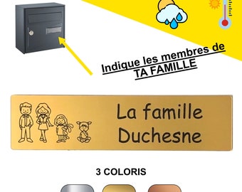 May include: A gold-colored rectangular nameplate with family illustrations and the text "La famille Duchesne." The nameplate also features illustrations of a family and the text "Indique les membres de TA FAMILLE." Three color options are shown below.