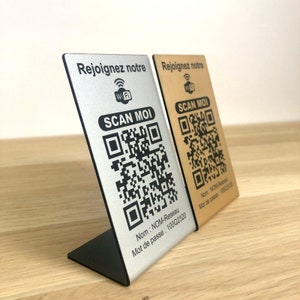 May include: Two metal WiFi signs with QR codes. One is silver, the other gold. Both signs read "Rejoignez notre", "Scan Moi", and include network information. The silver sign is on a black stand.