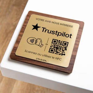 Peut inclure: Plaque rectangulaire en bois avec une plaque métallique dorée. La plaque présente le logo Trustpilot, une étoile et un code QR. Le texte comprend "VOTRE AVIS NOUS INTERESSE" et "Scannez ou utilisez le NFC".