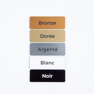 May include: Rectangular metal signs in bronze, gold, silver, white, and black. Each sign has a different color and the name of the color printed in a sans-serif font. The signs are arranged vertically against a white background.