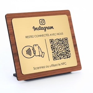 Puede incluir: Un letrero de Instagram de madera con una placa dorada. El letrero presenta el logotipo de Instagram, un código QR y el texto "Escanea o usa NFC". El letrero está diseñado para ser exhibido en un mostrador o escritorio.