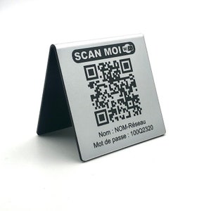 Op de afbeelding: Zilveren metalen wifi-bord met een zwarte basis, met een QR-code en de tekst "SCAN MOI". Onder de QR-code staan de woorden "Nom: NOM-Réseau" en "Mot de passe: 100Q2320".