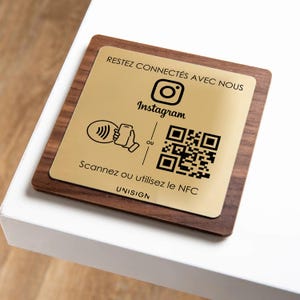 Peut inclure: Un panneau carré en bois avec une plaque métallique dorée. La plaque présente le logo Instagram, un code QR et le texte "RESTEZ CONNECTÉS AVEC NOUS" et "Scannez ou utilisez le NFC".