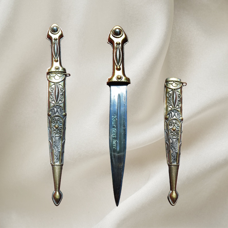 May include: Three ornate silver and gold daggers with intricate designs. The middle dagger has the text "Your text here" engraved on the blade.