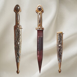 May include: Three decorative daggers with ornate gold and silver designs. The middle dagger has the inscription "My soul is always with you" on the blade.