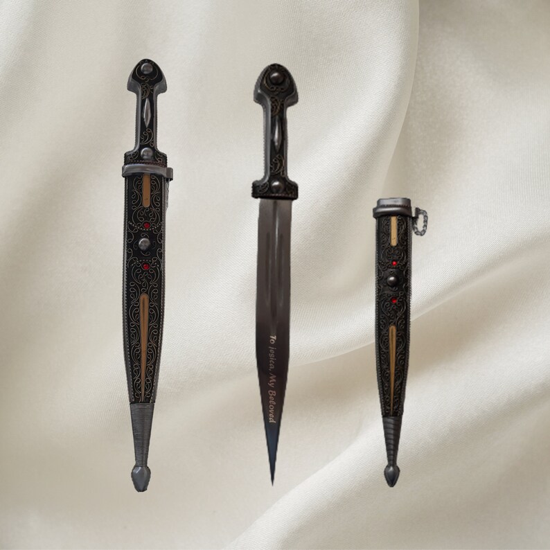 May include: Three decorative daggers with intricate designs and gold accents. The center dagger has the inscription "To Justice, My Beloved".