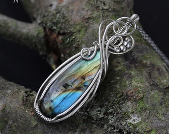 Silver pendant with natural labradorite Elongated pendant with a iridescent stone in a setting with swirls and small beads. Chain as a gift