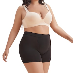 May include: A woman wearing a nude-colored bra and black shorts. The shorts have a wide waistband and a smooth, sleek fabric.