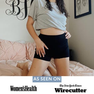 May include: A pair of solid black high-waisted shorts paired with a light gray short-sleeved t-shirt. Below the image, the text reads AS SEEN ON Women's Health and The New York Times Wirecutter, highlighting media features for the clothing items.