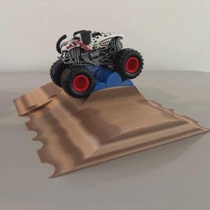May include: A toy monster truck with a dalmatian-themed design, red accents, and large black tires with red rims, is positioned on a brown ramp with a blue barrel obstacle. The toy is designed for play and is suitable for children.