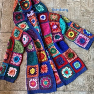 Puede incluir: Un cárdigan de ganchillo colorido con capucha, que presenta un diseño de patchwork de cuadrados en varios colores y patrones. El cárdigan está hecho con hilo azul y tiene un forro azul contrastante.
