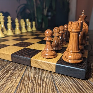 May include: A wooden chess set with brown and black pieces on a wooden chessboard. The pieces are arranged in a game in progress.