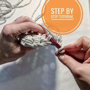 May include: Close-up of a person's hands crocheting a beige macrame project with a red crochet hook. The image includes the text "STEP BY STEP TUTORIAL".