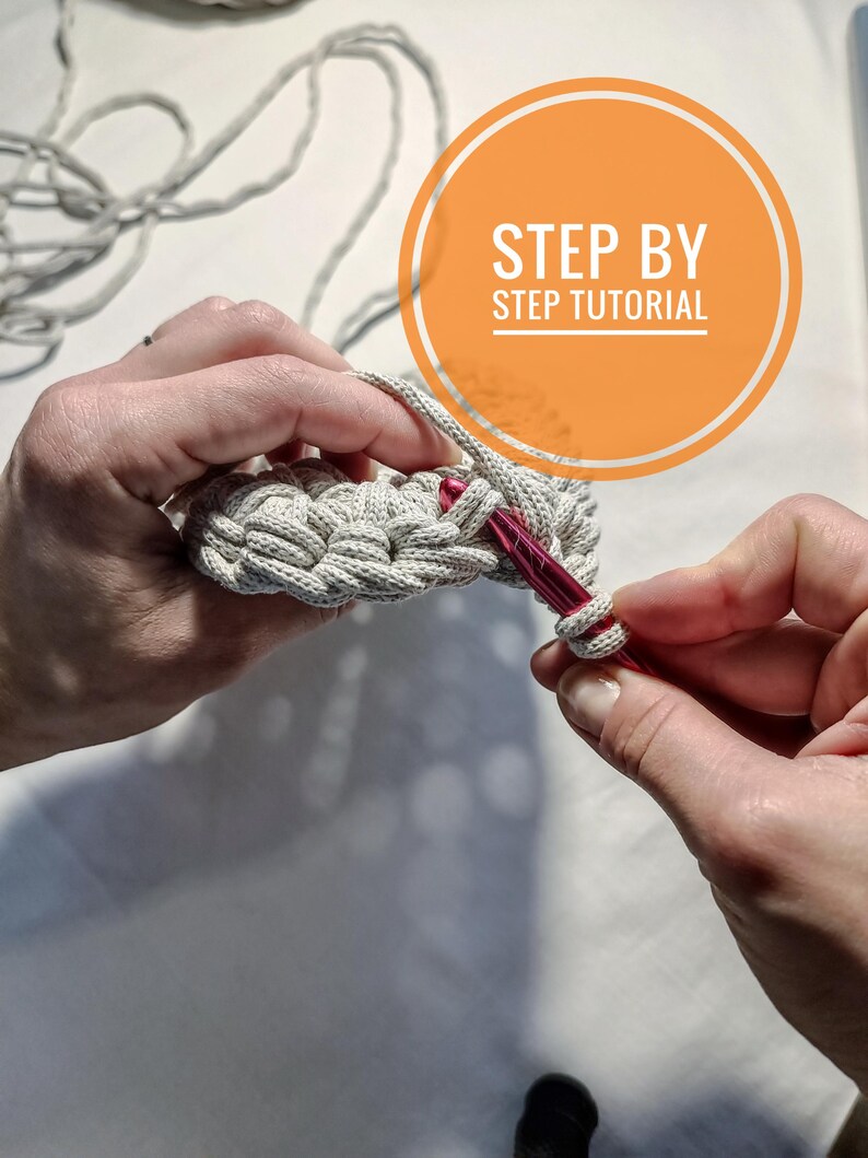 May include: Close-up of a person's hands crocheting a beige macrame project with a red crochet hook. The image includes the text "STEP BY STEP TUTORIAL".