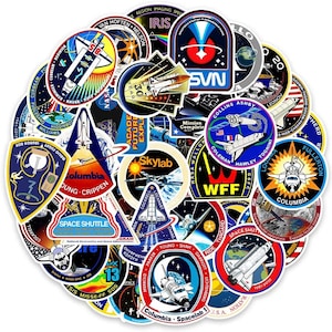 May include: A collection of colorful space-themed stickers featuring various NASA mission patches, space shuttles, and celestial imagery. The stickers include text such as "Columbia", "Space Shuttle", and "Skylab".
