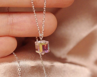 May include: A silver chain necklace with a small iridescent cube pendant.