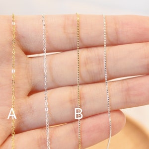 May include: Four delicate chains with letter charms, two gold and two silver. The chains are displayed on a hand, with the letter 'A' on the leftmost chain and the letter 'B' on the rightmost chain.