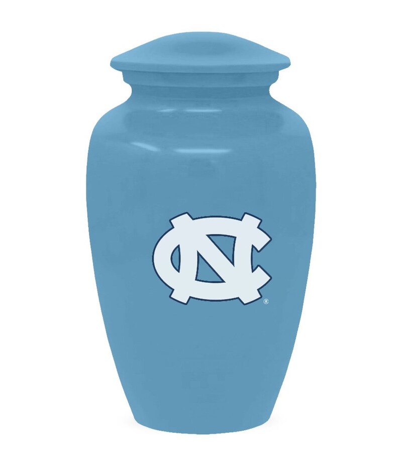 K&ouml;nnte beinhalten: Eine hellblaue Keramikurne mit einem wei&szlig;en und blauen Logo der North Carolina Tar Heels.