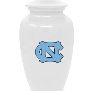 K&ouml;nnte beinhalten: Wei&szlig;e Keramikurne mit einem blauen und wei&szlig;en Logo der University of North Carolina Tar Heels.
