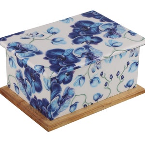 May include: A white wooden box with a blue and white floral design. The box has a hinged lid and a wooden base.