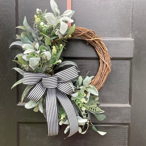 grapevine wreath with artificial mixed greenery, lambs ear, white floral accents, and large black and white striped bow