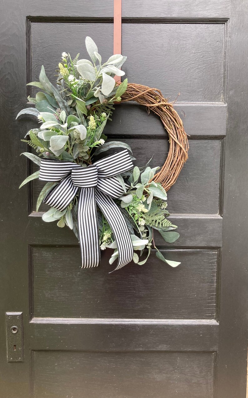 grapevine wreath with artificial mixed greenery, lambs ear, white floral accents, and large black and white striped bow