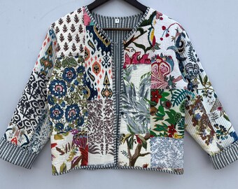 Op de afbeelding: Een wit katoenen jack met een patchwork-ontwerp met verschillende bloemen- en geometrische patronen in tinten blauw, groen, rood en oranje. Het jack heeft een ronde hals en driekwart mouwen.