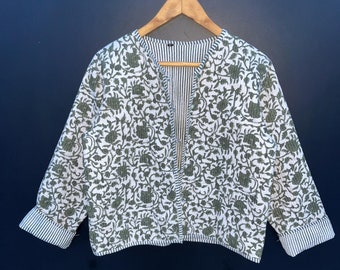 May include: A white and green floral patterned jacket with a button closure. The jacket has a striped lining and is hanging on a wooden hanger.