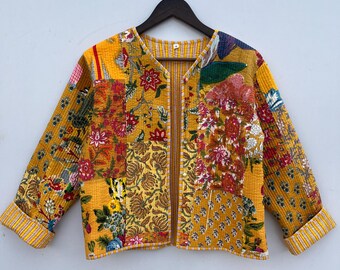 Op de afbeelding: Een geel gewatteerd jack met een bloemig patchwork-ontwerp. Het jack heeft een V-hals en lange mouwen met gestreepte manchetten.