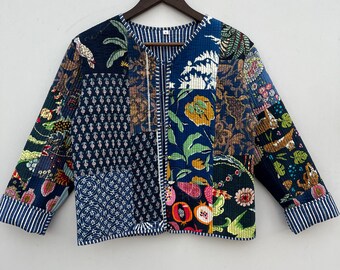 Op de afbeelding: Een blauw en wit gewatteerd jack met een patchwork-ontwerp met bloemen- en geometrische patronen. Het jack heeft een V-hals en lange mouwen.