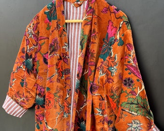 May include: A long, orange velvet robe with a floral print. The robe has a white and pink striped lining and a tie closure.