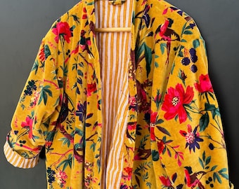 May include: A long yellow velvet robe with a floral print featuring birds, flowers, and leaves. The robe has a striped lining and a shawl collar.