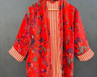 May include: A red velvet kimono with a floral and bird print. The kimono has a contrasting orange and white striped lining.