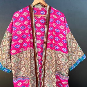 May include: A pink and brown patterned kimono with a geometric design. The kimono has a long sleeve and a tie closure.