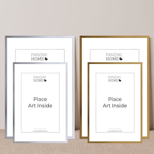 Könnte beinhalten: Zwei Bilderrahmen-Sets, eines silberfarben und eines goldfarben, jeweils mit weißem Passepartout und dem Text "Place Art Inside". Die Rahmen sind von Pandiki Home.